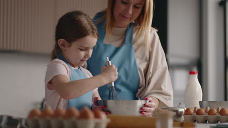 Kleines-Mädchen-Lernt-Kochen-Und-Hilft-Ihrer-Mutter-In-Der-Küche-Beim-Kochen-Zu-Hause,-Einer-Frau-Und-Ihrer-Tochter
